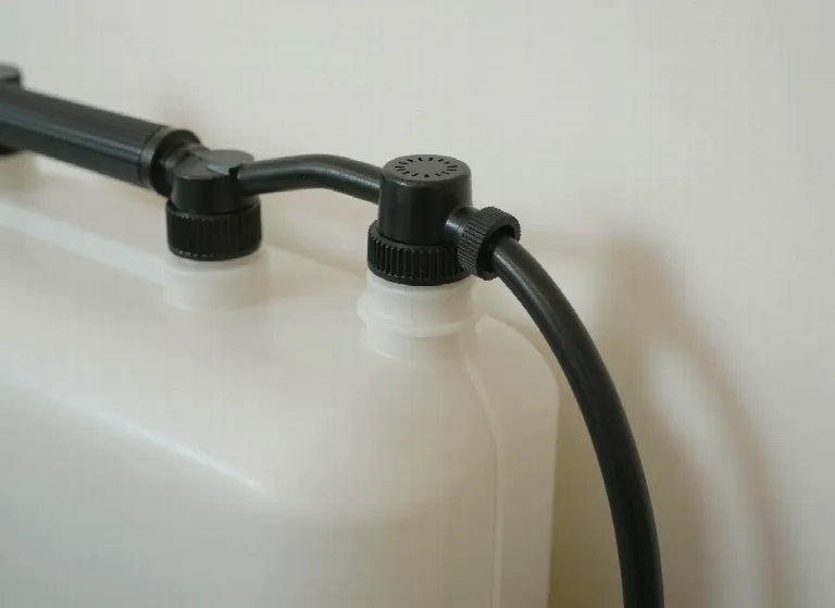 Detailaufnahme des Tanks eines Drucksprühgeräts mit Pumpenhebel, Anschlüssen und Schlauch.
